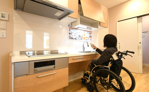 リモコン操作で吊戸棚を上下に動かせる仕組みを示した写真。座ったままでも収納にアクセスしやすい機能を紹介。